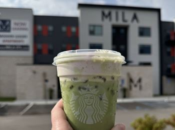 Iced matcha latte with property signage in background
